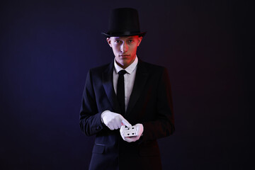 Illusionist showing trick with playing cards on dark background