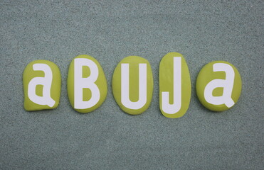 Abuja, capital city of the Federal Republic of Nigeria, creative logo composed with hand painted green stone letters over green sand
