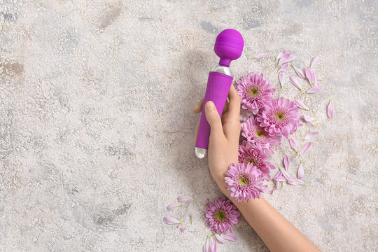 Female hand holding clitoral sex toy on grunge background