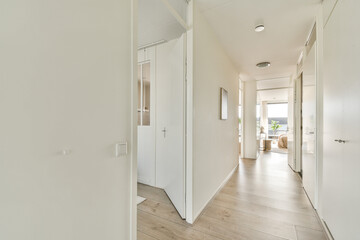 A bright and spacious hallway showcasing minimalist design with wooden flooring, white walls, and...