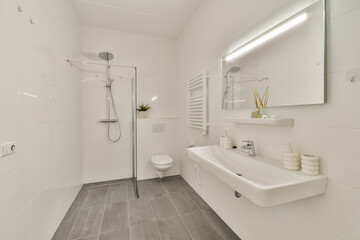 A sleek minimalist bathroom featuring a glass shower, modern sink, and elegant decor. The design emphasizes cleanliness and functionality with neutral tones.
