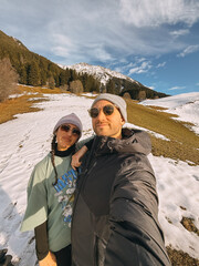 Tourists enjoying winter holidays in a snowy mountain landscape, capturing a selfie against a...