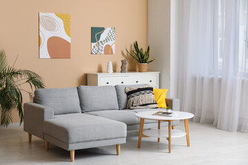 Comfortable sofa, coffee table and picture hanging on beige wall in living room