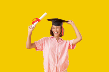 Female graduating student with diploma on yellow background