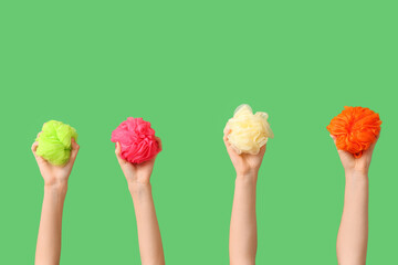 Female hands with different bath sponges on green background