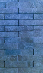The brick wall is blue. Brick blue background. The texture of the blue brick. Vertical image.