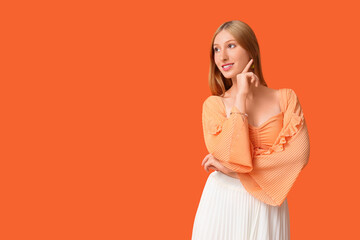 Obraz premium Beautiful young happy woman in stylish summer outfit on orange background