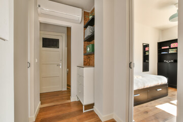 Bright and airy modern interior hallway showcasing minimalist design elements and ample natural light, leading to a cozy bedroom area.