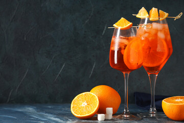 Glasses of Aperol spritz cocktail with fruits and sugar on blue background