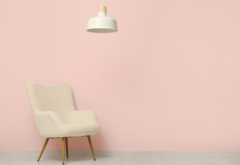 Hanging lamp and armchair near pink wall in room