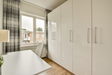 Elegant minimalist interior showcasing sleek white cabinets and a bright workspace, complemented by natural light and contemporary décor.