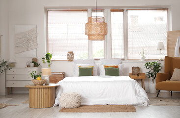 Interior of cozy bedroom with armchair, tables and window