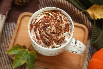 Autumn composition with cup of cocoa and wooden tray on plaid as background, closeup