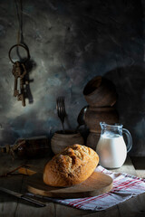 Fresh wheat bread and milk in glass jug on rustic table