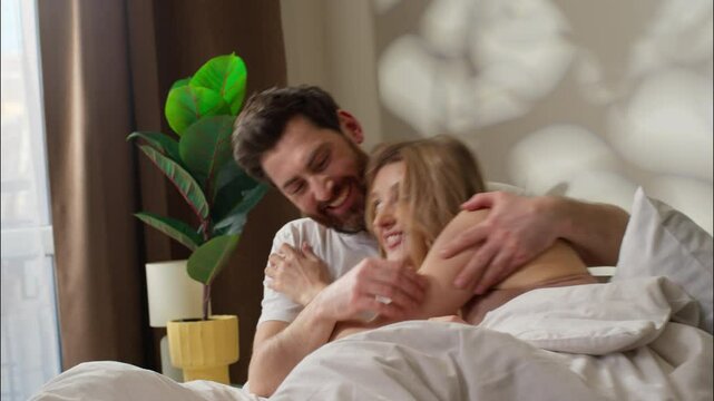 Family love carefree Caucasian couple lying on bed cozy morning at home happy woman hugging affectionate pair enjoy closeness together man embracing girl guy smile relaxing bedroom bonding tenderness