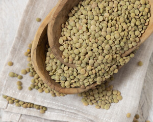 Wooden bowls full of dried green lentils on white table top view. Traditional mediterranean legume
