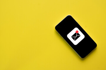 Flat lay of New email message notification icon on smartphone screen over yellow background with...