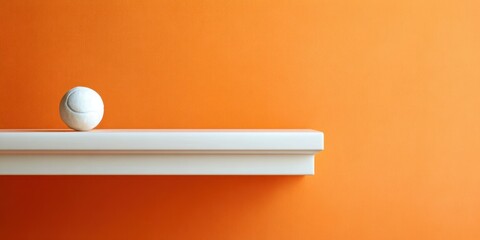 A white tennis ball sits on a shelf in front of a wall