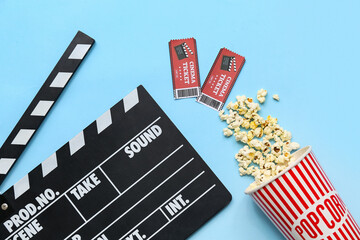 Movie clapper with cinema tickets and popcorn on blue background