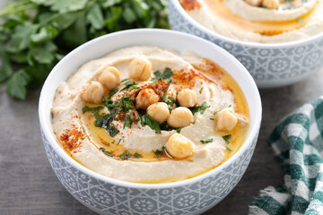 Chickpea hummus with olive oil, parsley and paprika in bowl on wooden table