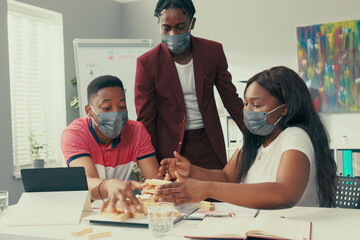 Break in the office from work, two young interns are building tower of wooden blocks at the desk,...