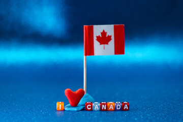 Creative display of a Canadian flag with love heart and letter blocks on blue background for...