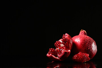 Tasty ripe pomegranates on black background