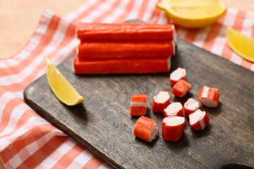Wooden board with tasty crab sticks and cut lemon on beige background © Pixel-Shot