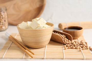 Bowl with pieces of tofu cheese on white background