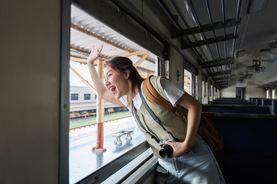 Dynamic Travel and Enthusiasm. A woman waves goodbye from the window of a train, embracing the joy of travel.