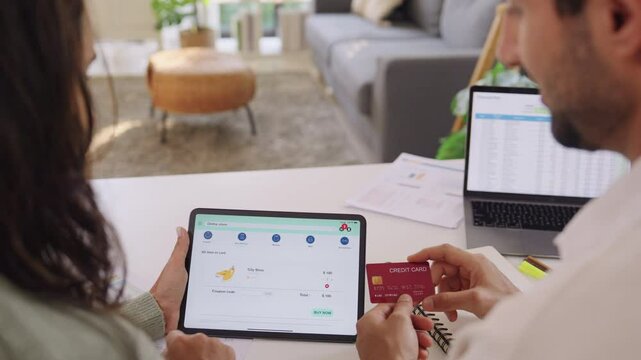 Couple using tablet and credit card to shop online through e-commerce app, making payment and browsing modern platform with promo codes and discount offers
