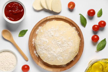 Ingredients for preparing pizza with mozzarella, wooden plate and raw dough on white background