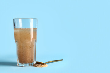 Glass of water with psyllium husk on light blue background