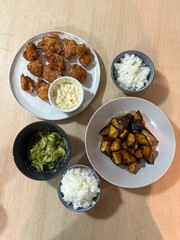A meal of fried chicken, eggplant, cucumber, and rice.