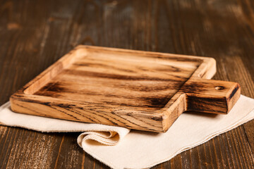 Empty cutting board with napkin on wooden table, top view
