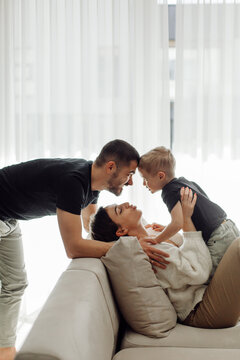 Happy family bonding on the sofa: father and son showing affection to mother