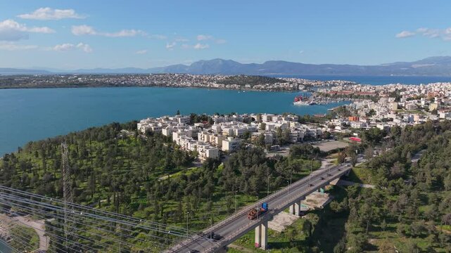 Chalkida city shines under the sun as the camera slowly reveals the iconic High Bridge in the distance. A bright and scenic view of coastal urban life in Greece