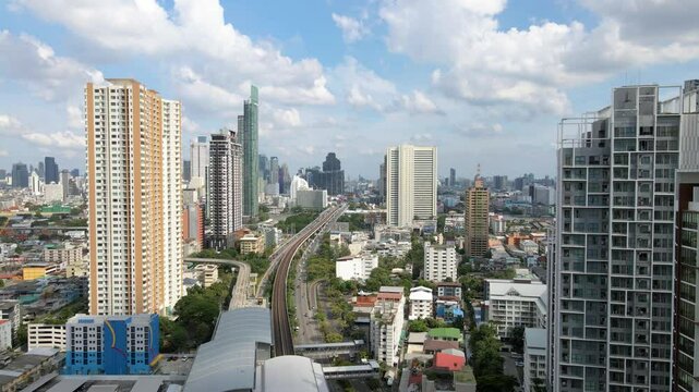 Drone flyover Krung Thon Buri Skytrain station toward east Bangkok, with bright sky