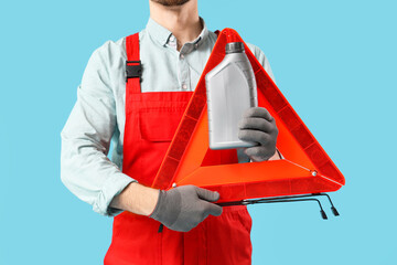 Male mechanic with canister and emergency stop sign on blue background