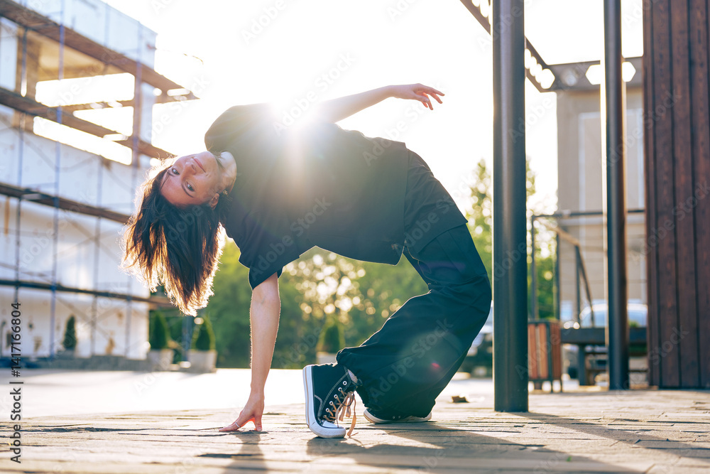 Poster dancer performs a unique move in urban setting during sunset in the city