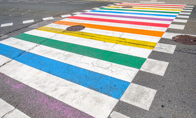 Colorful crosswalk decorated with rainbow stripes in a vibrant urban setting on a sunny day