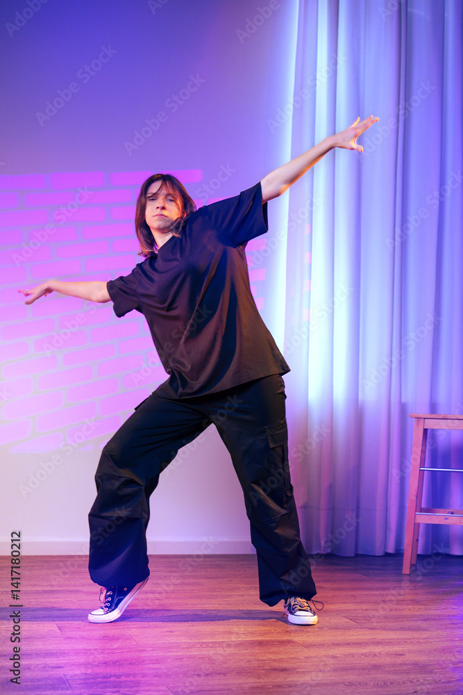 Poster dance performance featuring a person in casual black attire against a colorful backdrop in a studio 
