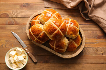 Tray with Easter cross buns, knife and butter on wooden background