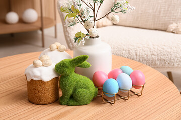 Vase with tree branches, Easter cakes, rabbit and eggs on table in living room, closeup