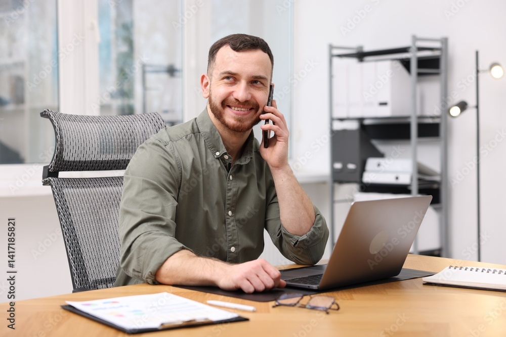Poster man talking on phone while working at desk in office