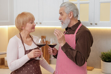 Senior couple with glasses of wine in kitchen