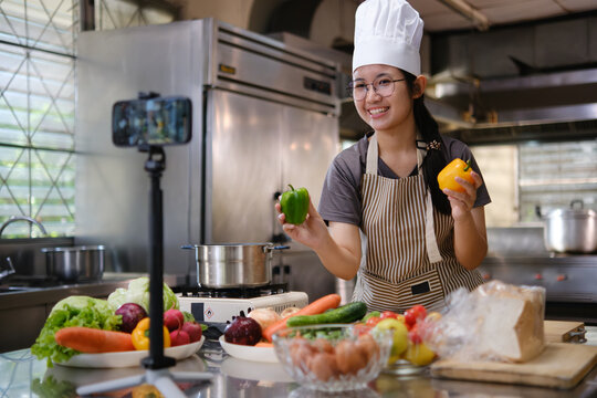 Food vlogger filming a cooking video in professional kitchen studio.