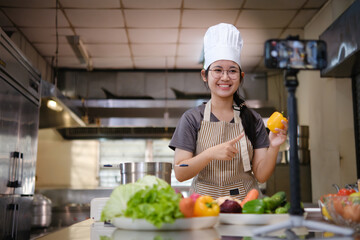 Food vlogger filming a cooking video in professional kitchen studio.