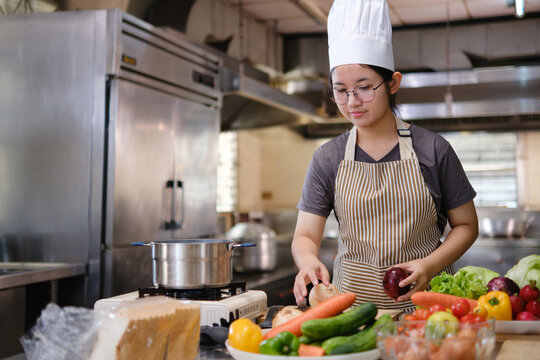 Culinary student standing confidently in training kitchen with fresh ingredients ready for cooking practice