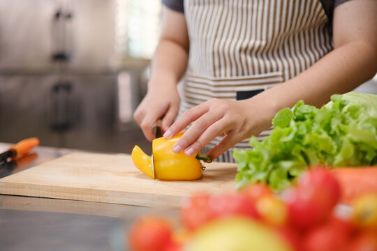 Young woman slicing vegetables in kitchen.